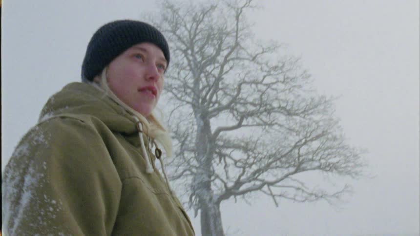 A young woman stands in a snowy field