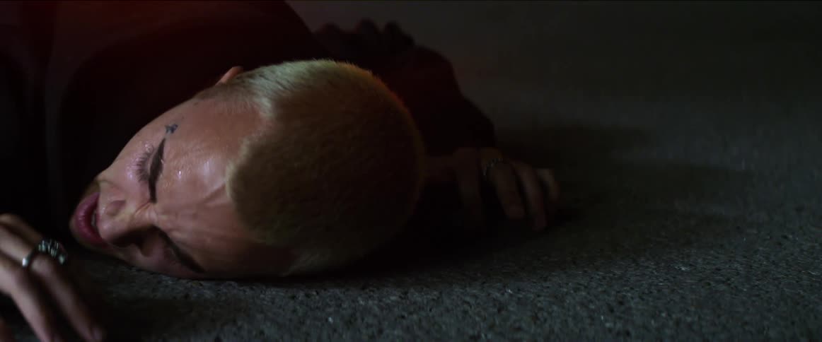 A young man lying face down on the street crying and talking