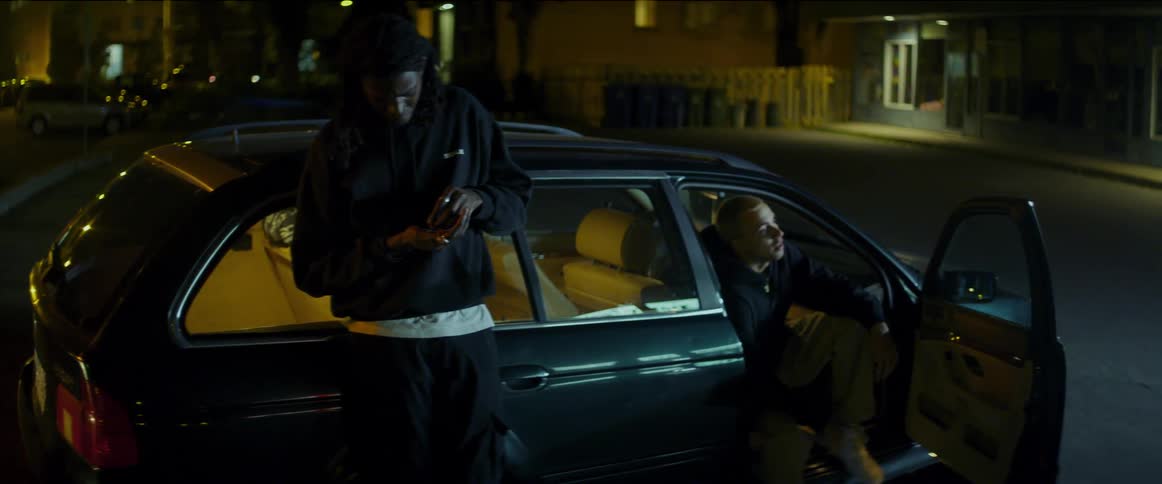 A man approaches a vehicle where a group of friends sit and chat