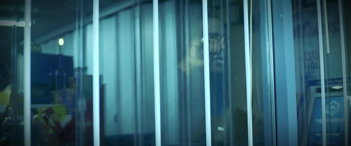 A man has his hands pressed on the glass and is looking in to a store enclosed with class