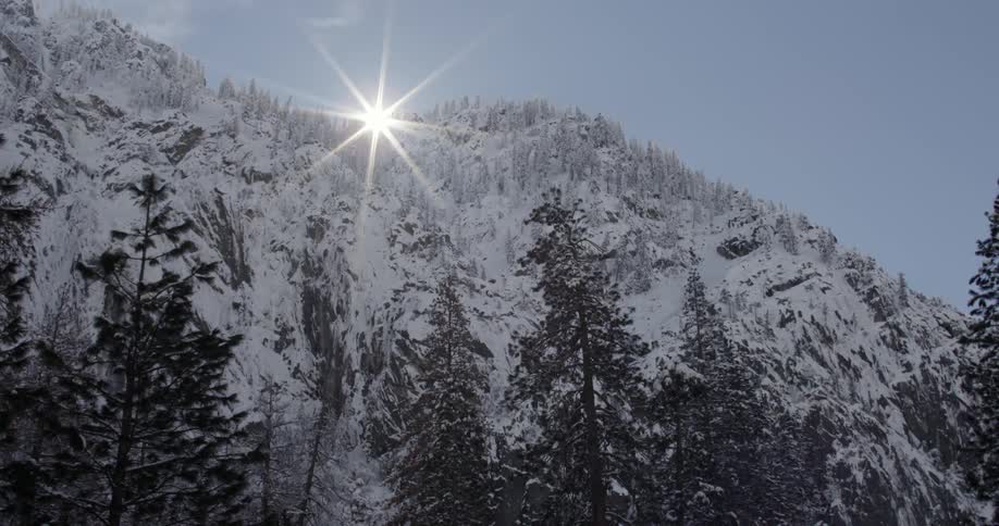 The sun shines over a snow-covered mountain