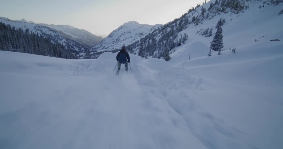 A skier lands a flip off a snow ramp while skiing down a mountain slope
