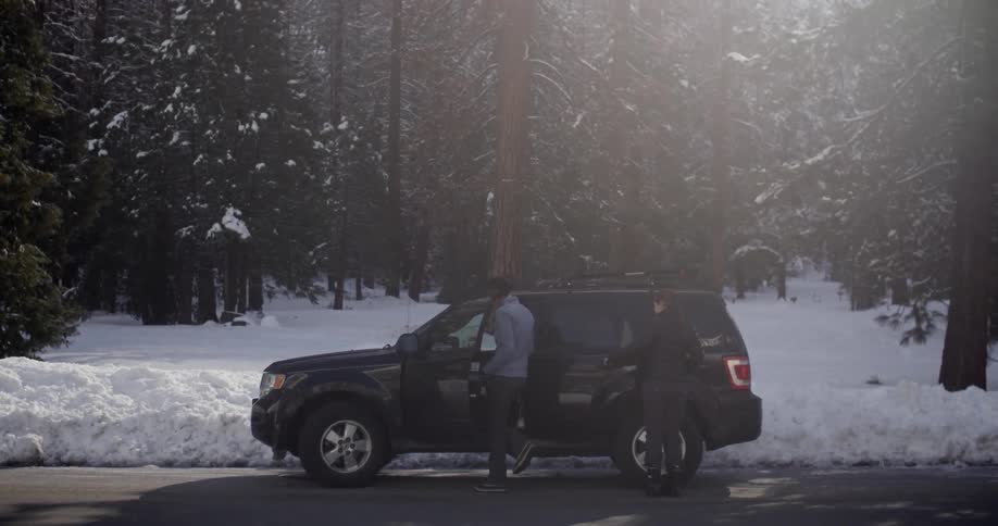 Three people climb into a black vehicle