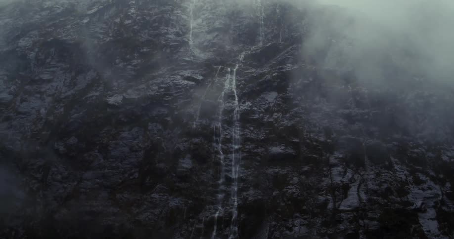 Water pours down a foggy mountain