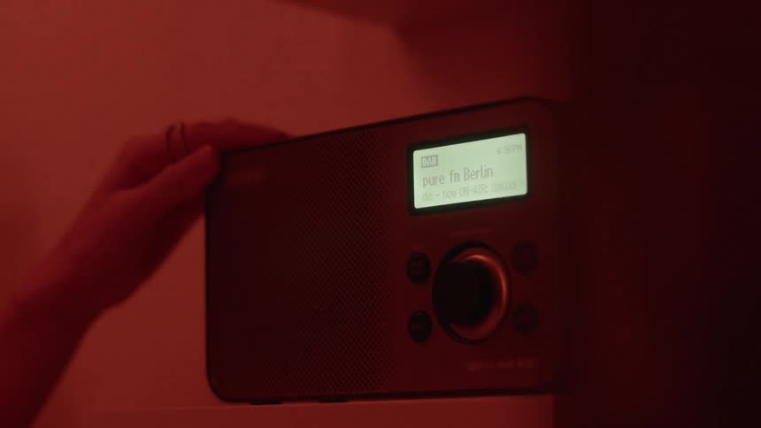 A person taps the top of a vintage radio to turn it off