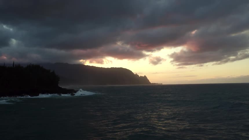 The ocean tides move as tall cliffs and a shoreline come into view