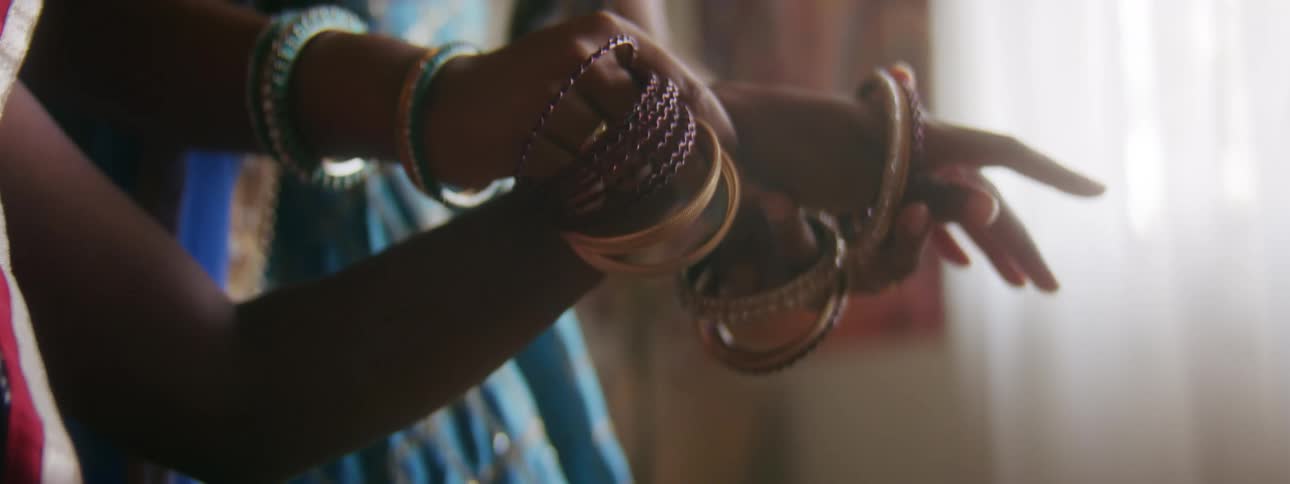 One woman places several bracelets on the wrist of another woman