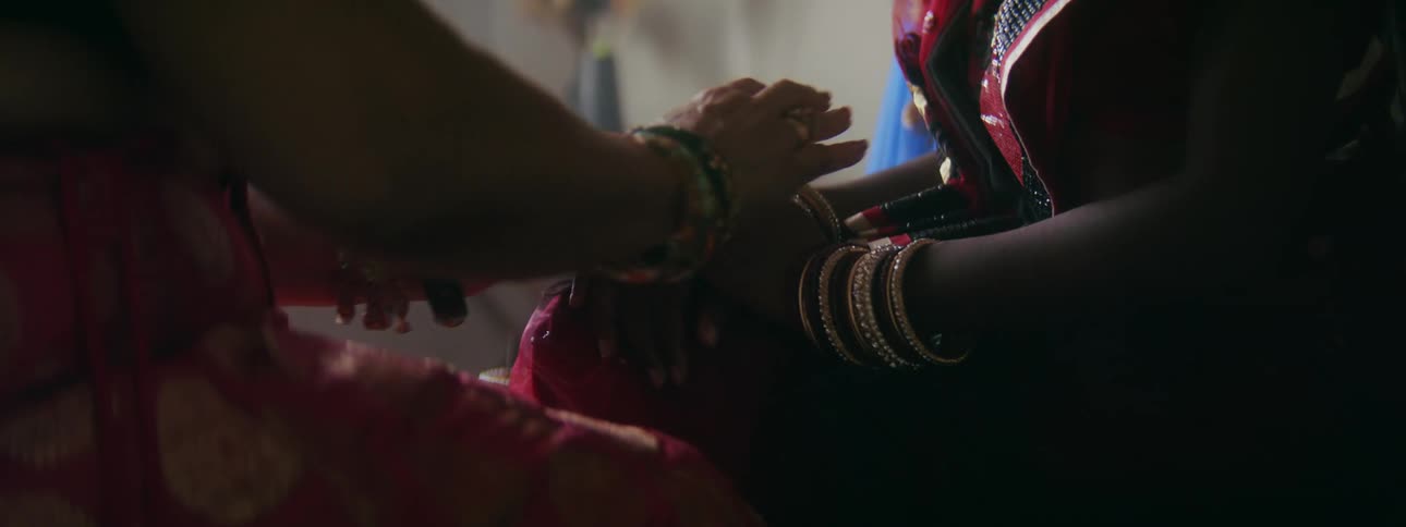 Two friends are holding hands and sitting indoors