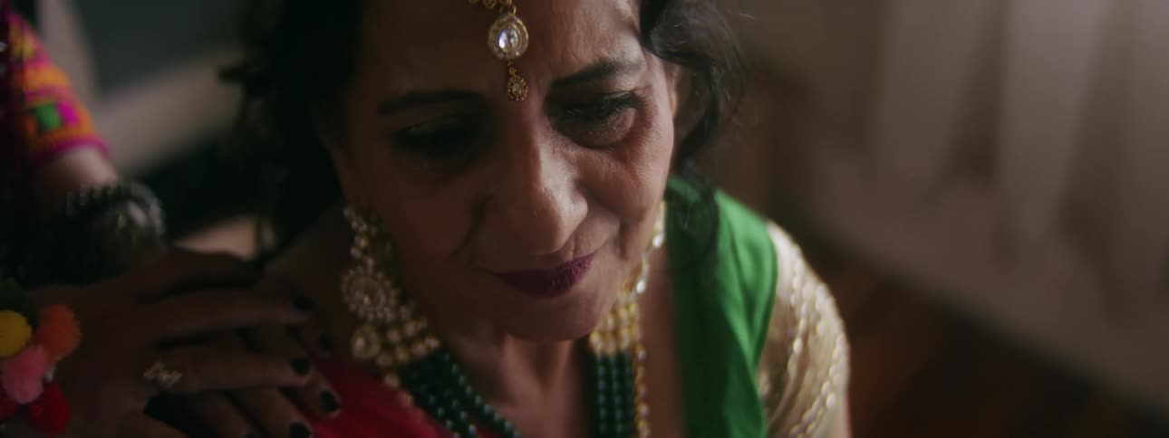Woman wearing finery sits crying as another stands and touches her shoulder in comfort