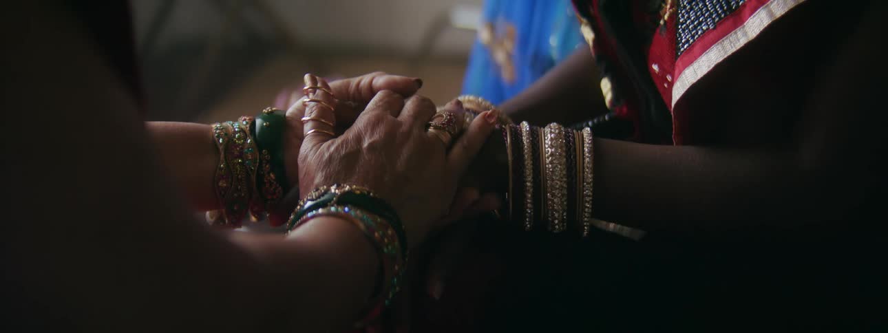 Older woman holds finely dressed younger womans hand reassuringly