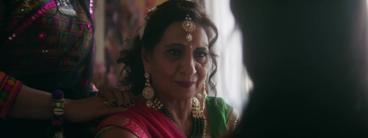 An older woman in traditional indian dress gets emotional as she caresses her daughters face and hair
