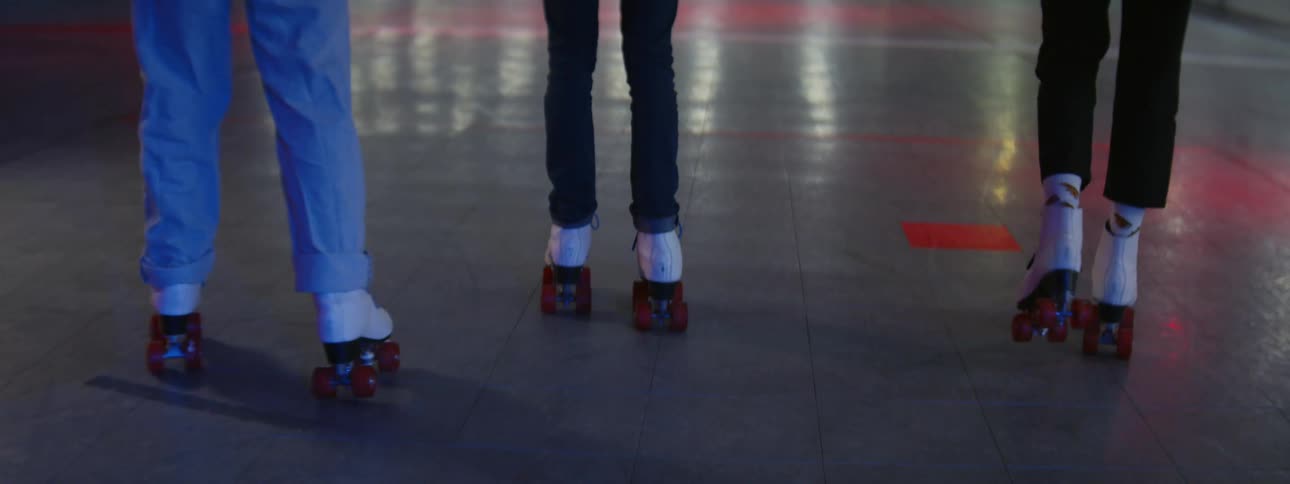 Three people roller skate side by side