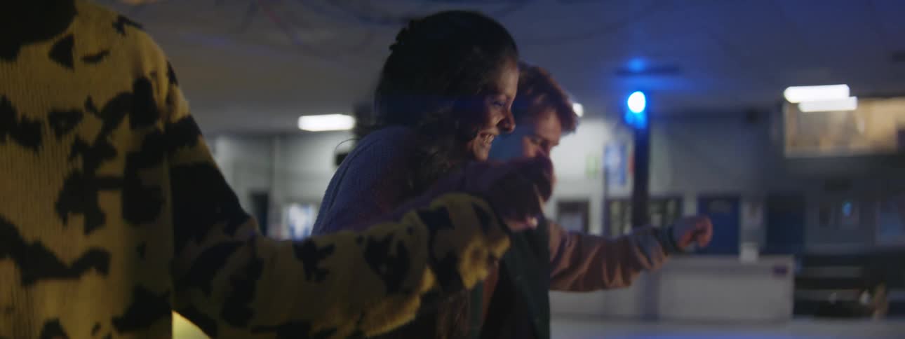 Friends hold hands while moving across skating rink