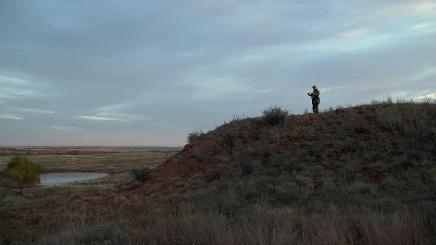 A person is standing on the top of a hill on a cloudy day