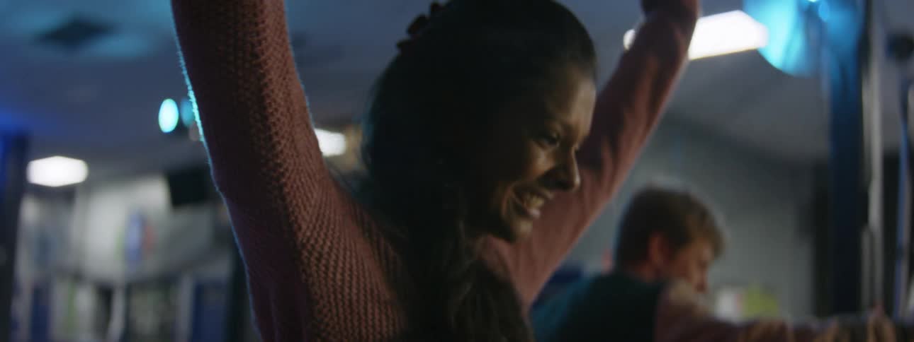 A woman smiles as she puts her arms up in the air to help her balance as she roller skates