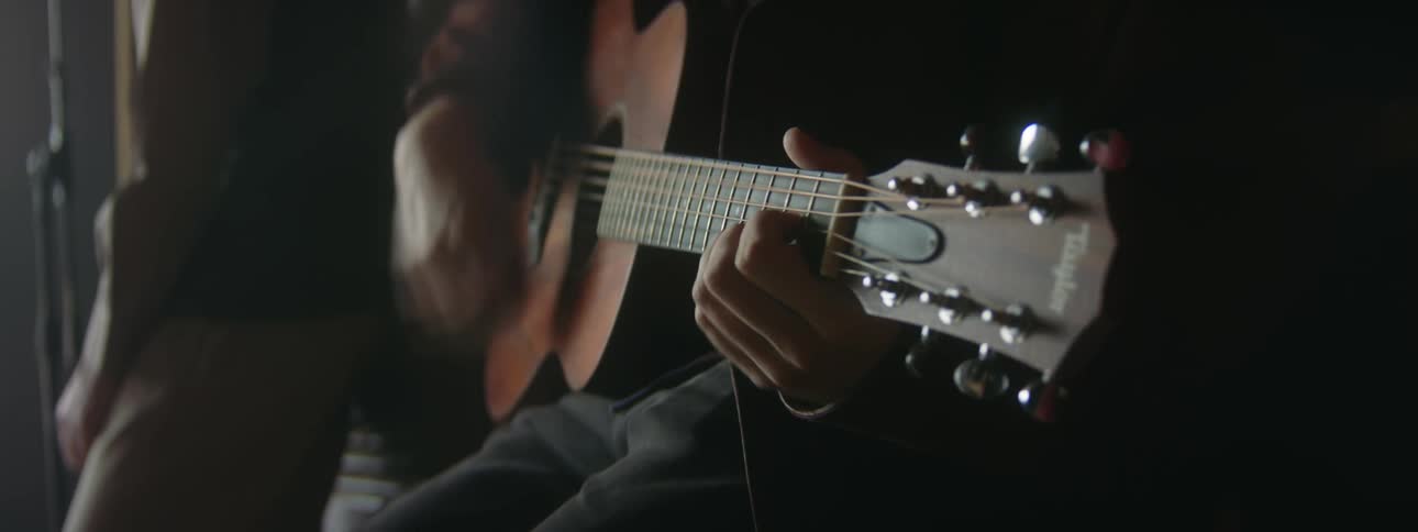 Close up of guitarist strumming on an acoustic guitar