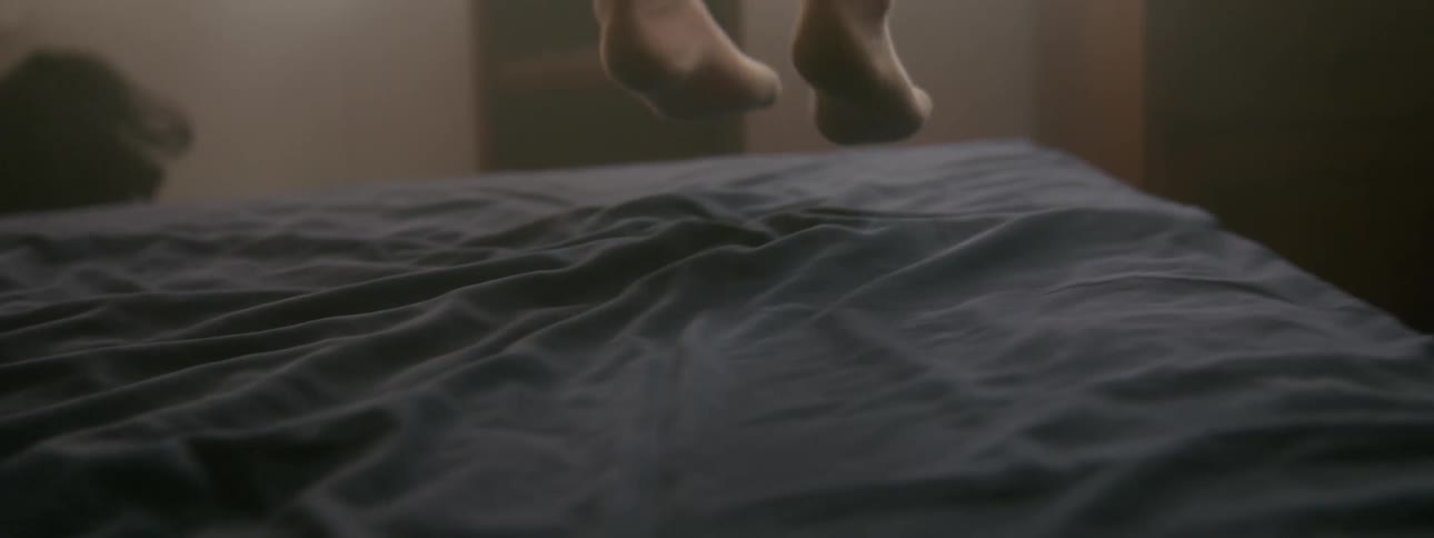 A child jumps on a bed