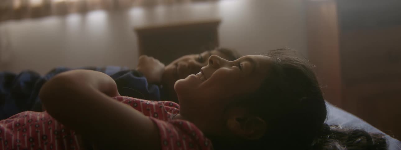 A brother and sister are laying down and laughing