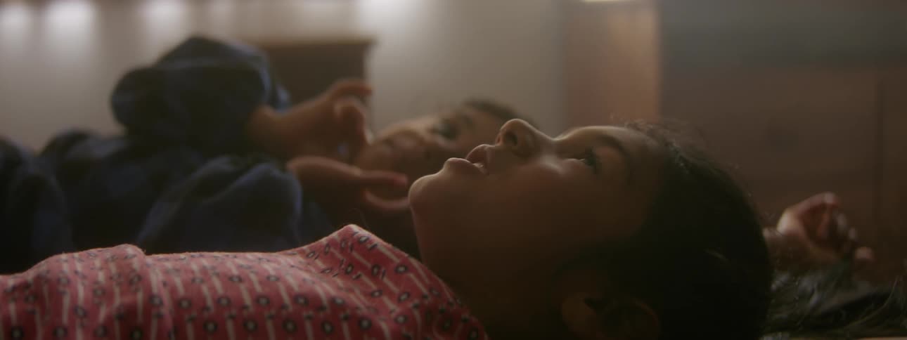 Sisters are laying in bed talking in a room