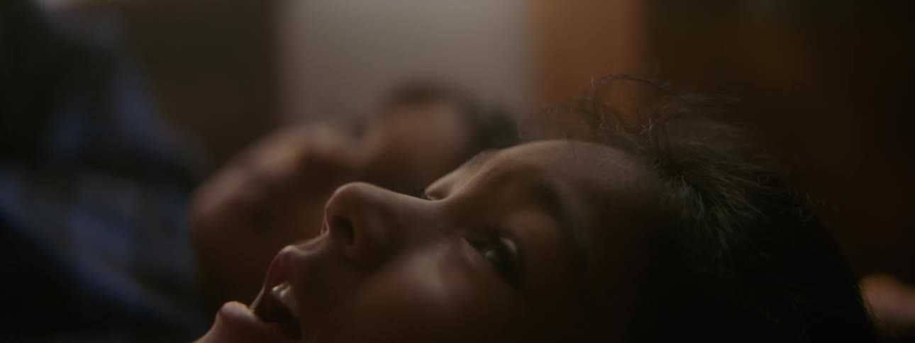 Two sisters lie side by side in bed and look at the ceiling