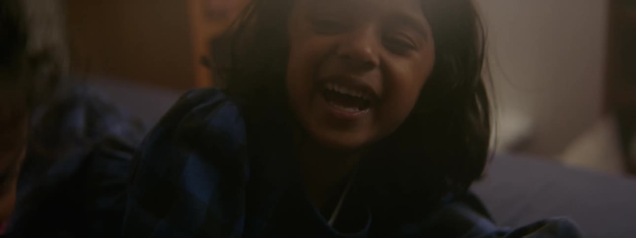 A little girl makes a face falling back on the bed then gets up laughing with her sister