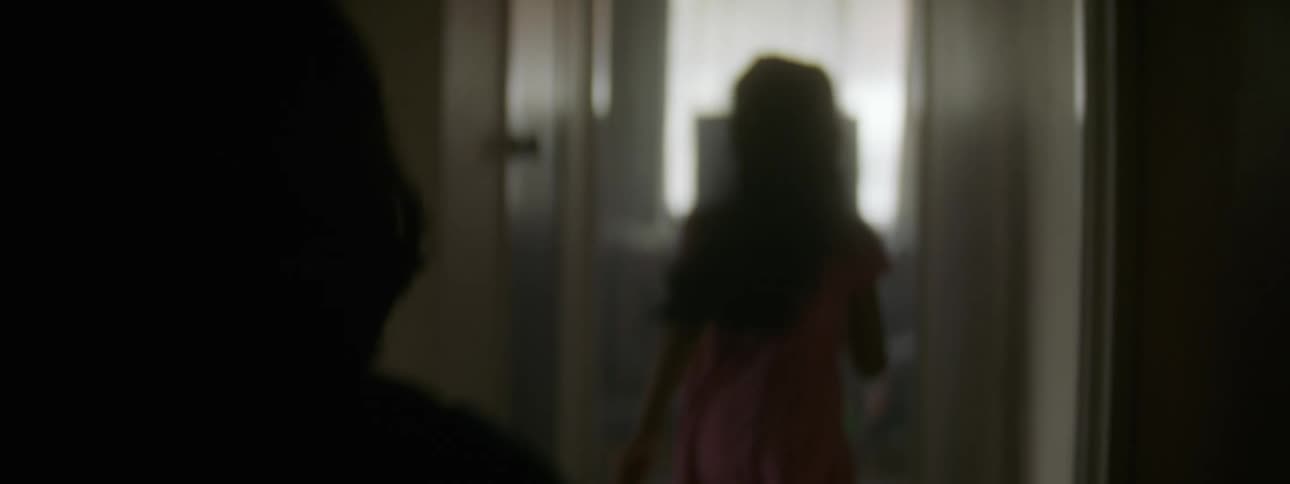 Two young children are running through the hallway of a home and their hair bounces as they run