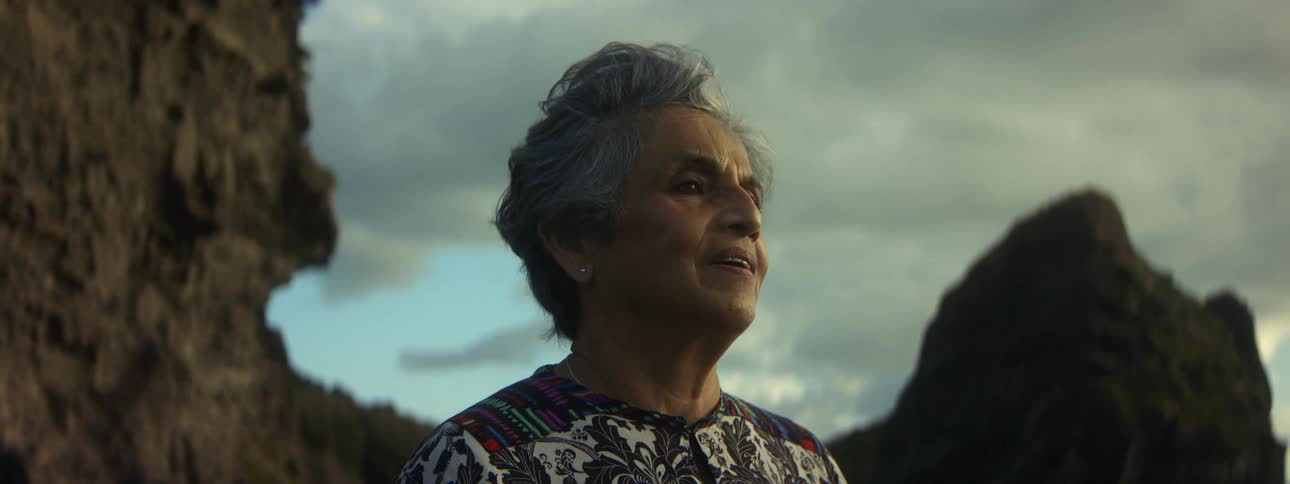 A woman standing on the beach takes a deep breath and closes her eyes face in the breeze