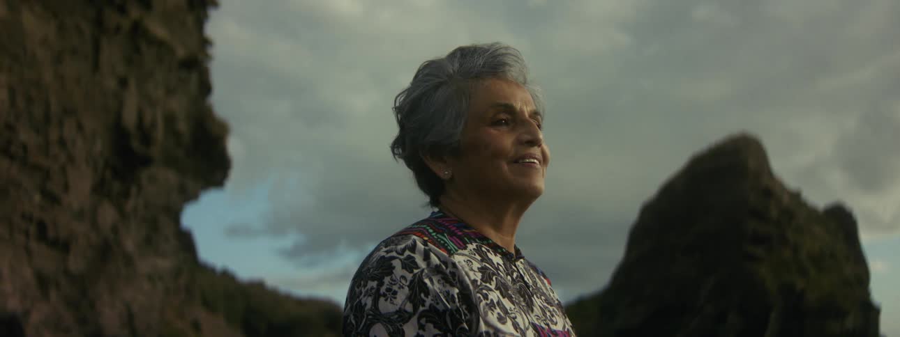 A woman standing alone on the beach takes a deep breath in relief smiling into the wind