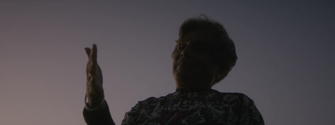 A woman takes a deep sighing breath as she releases the ashes in her hand