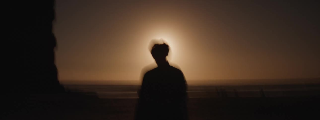 A man walks quickly past a cliff