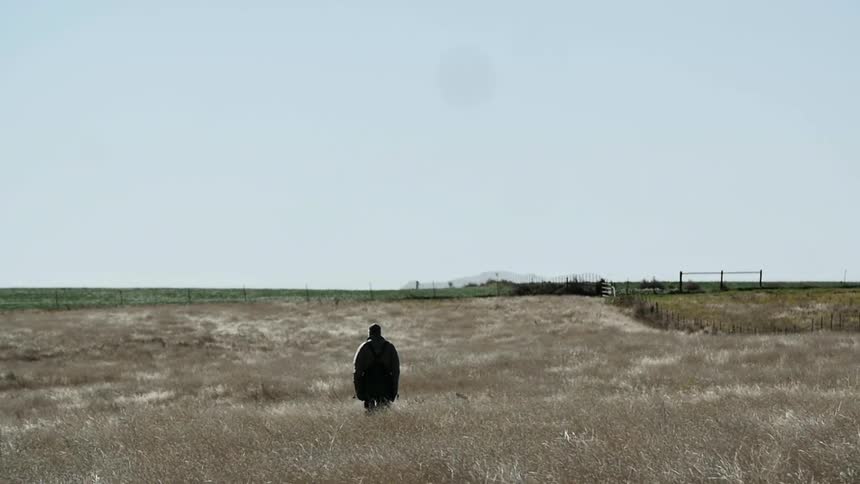 A man walks in a field on a clear day