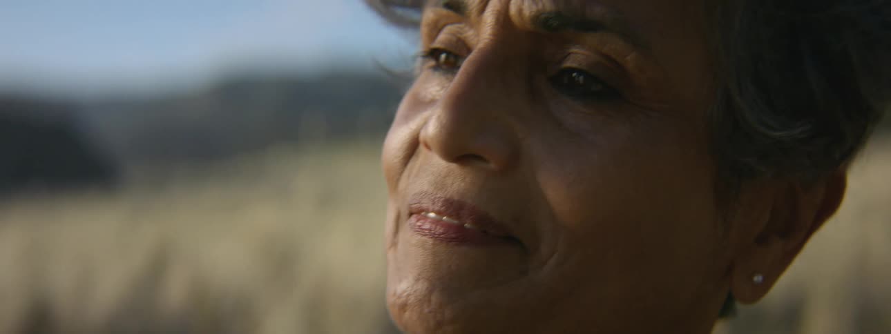 A woman is standing outside letting the wind her hair