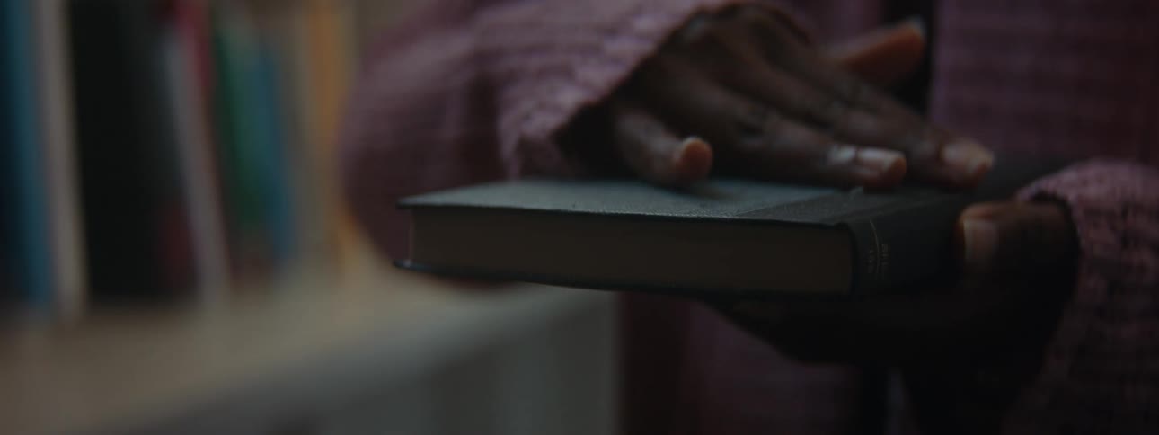 A woman is standing in a room and holding a book