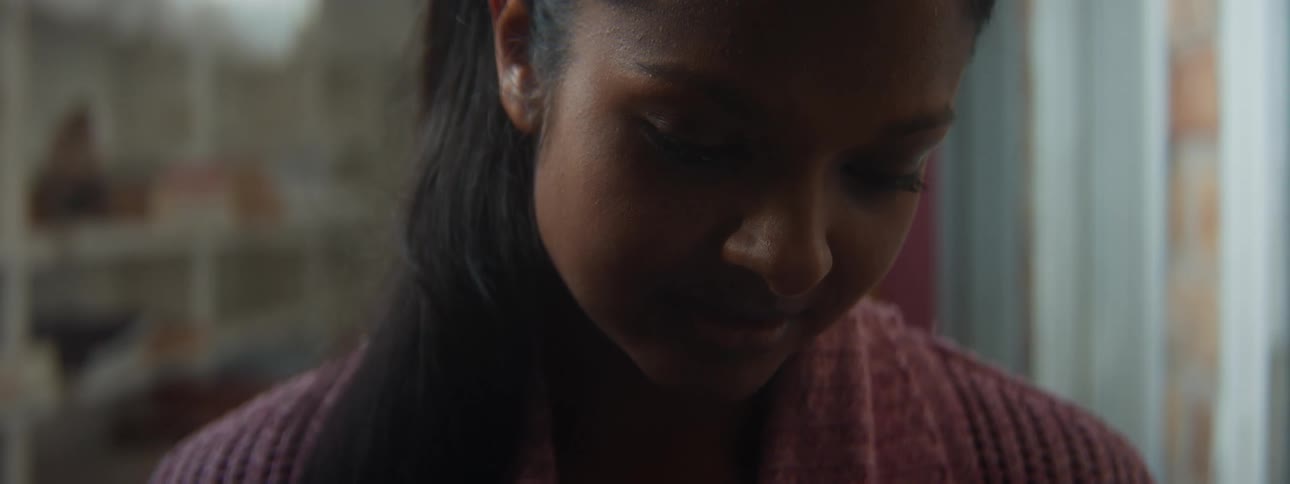 A woman is standing in a hallway looking down at something with a smile on her face