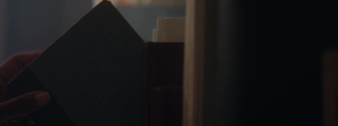 Girls hand with pink sweater takes book froom bookshelf