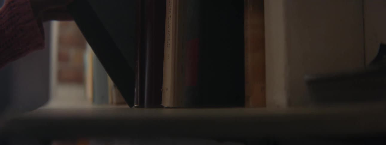 Woman pulling out an old book from a bookshelf