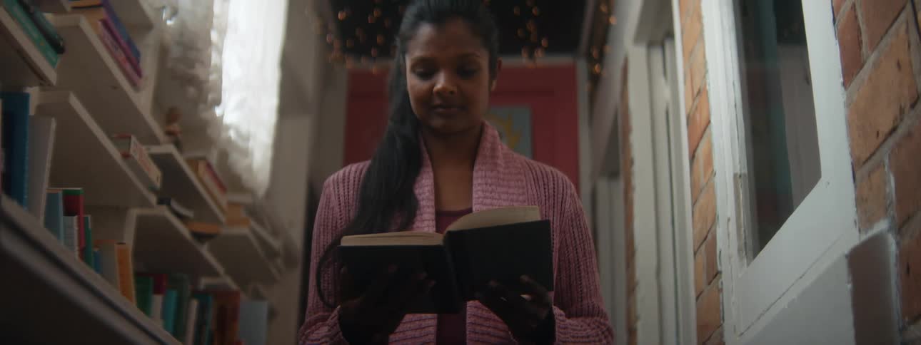 A woman is reading a book and standing in a room