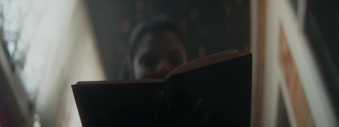 Close up of a woman opening a book inside a dimly lit room