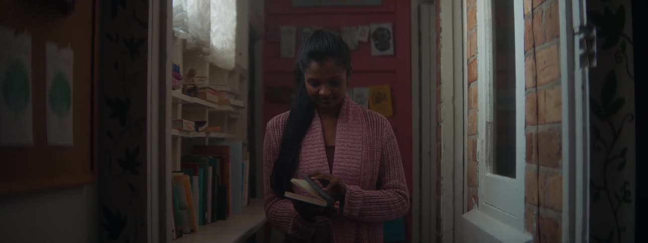 A young women is holding a book inside of her room
