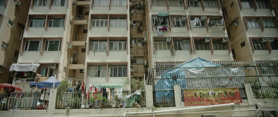 An apartment building with balconies and there are tents and a yard sale in front