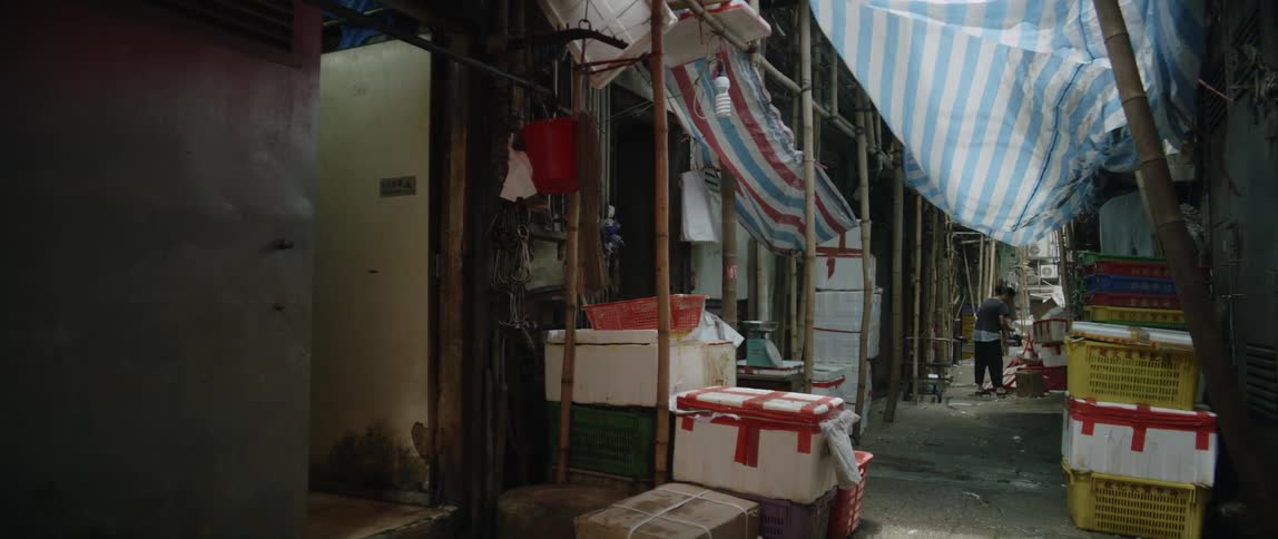 A woman at a street side shop bends down and takes something out of a box