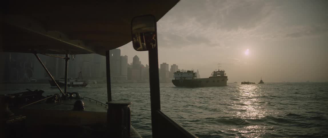 A boat is driving through the ocean water at dusk