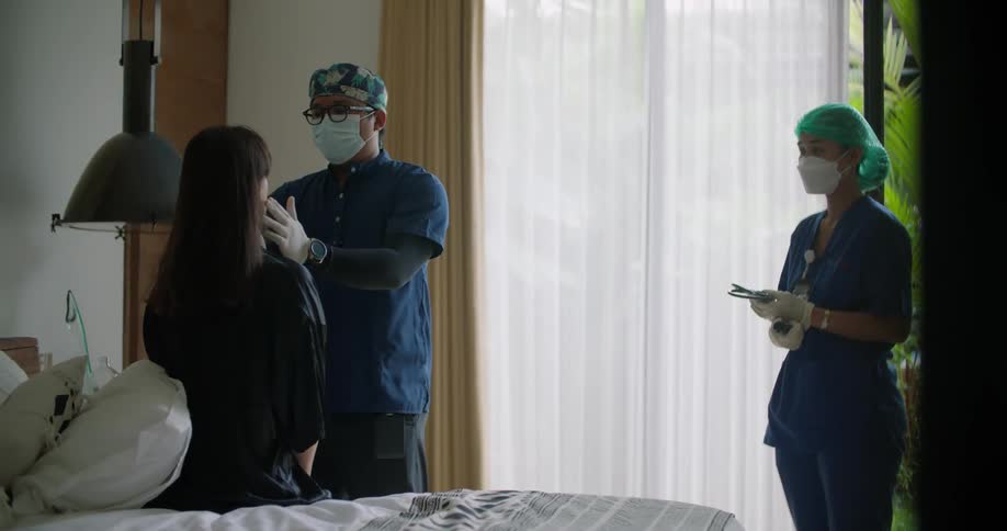 A doctor checks a patients neck during a home visit