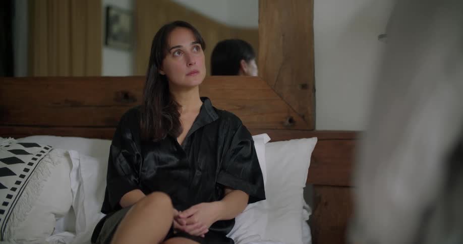 A woman nods while listening to her partner talk in their bedroom