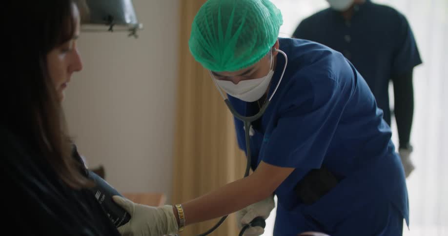 A doctor is checking on a patient at their home
