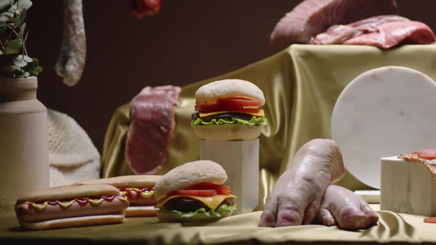 A meat display including hanging sausage and bacon burger and hot dogs along with pigs feet