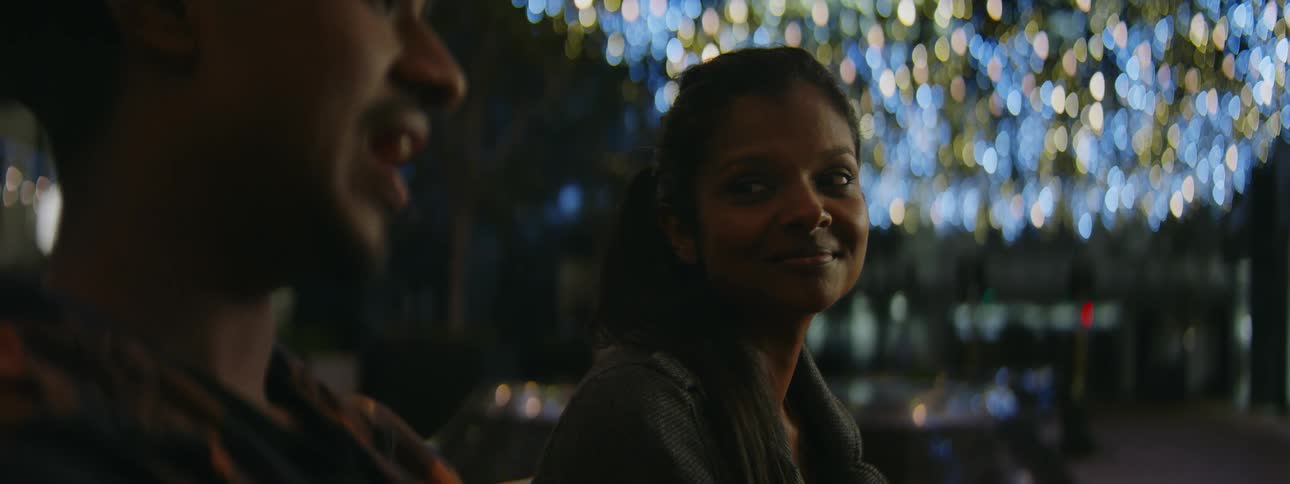 A man and woman chat while sitting at a bar