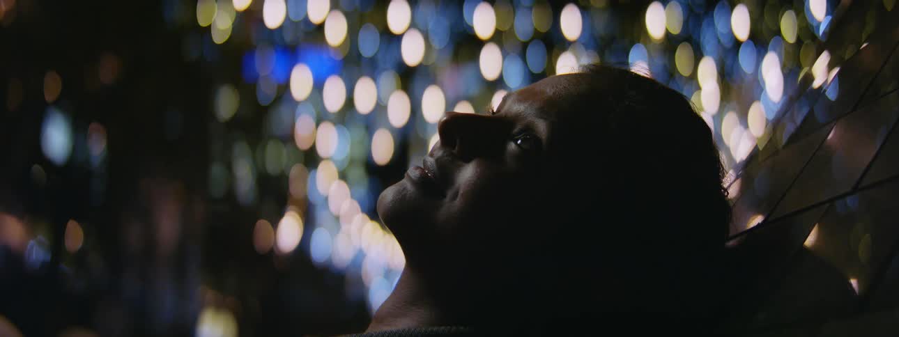 A woman lies outside at night and looks up at the sky