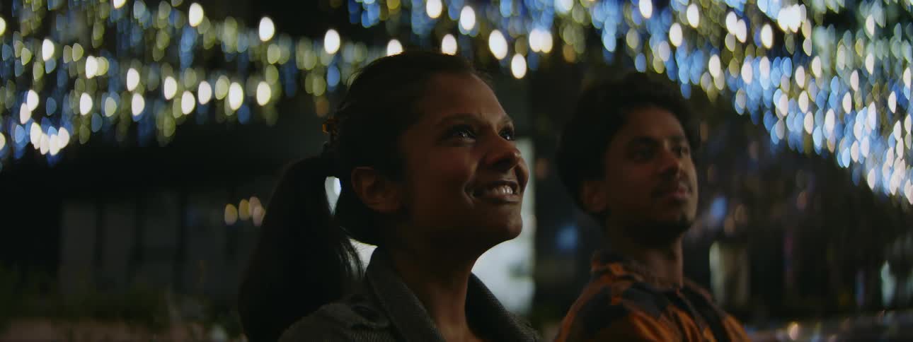 A woman smiles as she laughs and points out something to her male companion