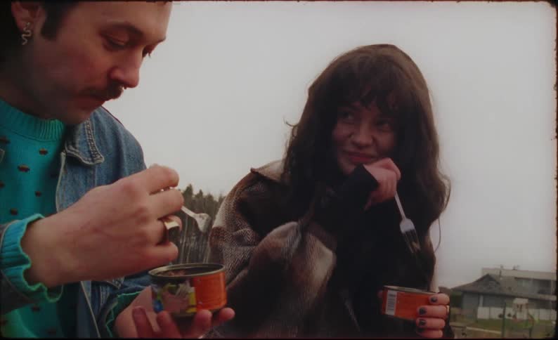 Two people sitting outside talking and eating